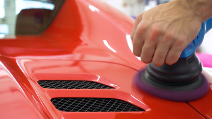 In the car center (in the garage), professionals polish a new sports car. Luxury car polishing....