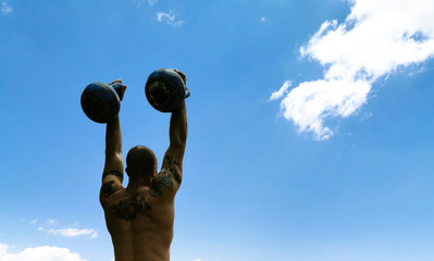 Man presses two kettlebells overhead