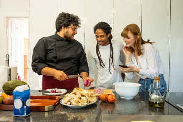 chef teaching a young couple of different breeds how to cook