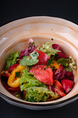 Close up traditional summer vegetable salad with fresh vegetables, tomatoes, pepper, greens, parsley, radish and olive oil in a bowl. Top view. Rustic style. Selective focus. Healthy food.