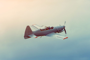 Single propeller aircraft aerobatic flying over the gray sky.
