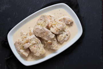 chicken with creamy sauce on dish on ceramic background