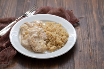 dish of meat with sauce and boiled quinoa on white wooden background