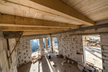 House room interior under construction and renovation. Energy saving walls of hollow foam insulation blocks, wooden ceiling beams and roof frame.