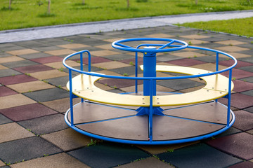Playground in kindergarten with soft flooring and colorful bright merry-go-round outdoors.