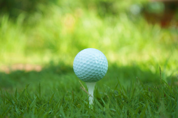 Golf ball on tee in beautiful golf course at sunset background.