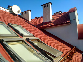 Red tiled house roof with attic windows. Roofing construction, window installation, modern...