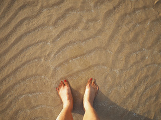 Selfie woman feet on beige sand summer sunset beach background.
