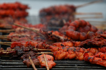 Skewer chicken pieces roasting on the grill and smoke.