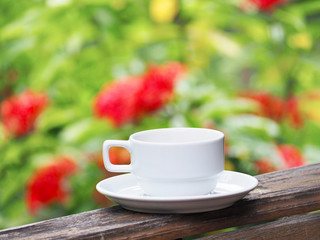 white cup of coffee over green floral abstract blur background.