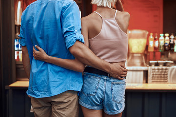 Backs of couple hugging while choosing food