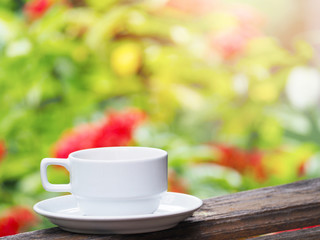 white cup of coffee over green floral abstract blur background.