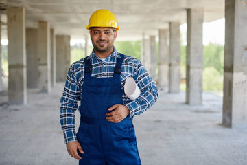 Smiling engineer in yellow construction helmet looks at the camera.