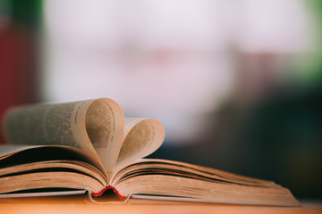Old book page decorate to heart shape for love in valentine day with blurred background and vintage color tone style. Composition of love with open book heart, Love of books, Library, education. 