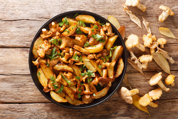 Delicious fried potatoes with chanterelles close-up on a plate. Horizontal top view