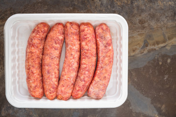 Fresh Raw Sausages in White Plastic Container Top View Close Up, Copy Space