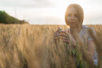 Woman holding wheat ears on the field.