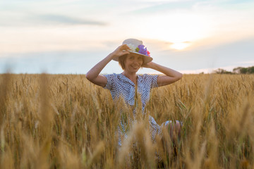 Free and happy woman in dress and hat on wheat field. Freedom, joy concept.