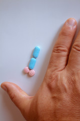Hands of a man next to pills that symbolize a penis with an erection. Metaphor of male virility. Medicine related to male impotence.