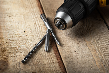 Electric drill closeup on a black background with wood and drills. Electrical tools. Hand battery screwdriver.