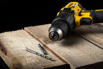 Electric drill closeup on a black background with wood and drills. Electrical tools. Hand battery...