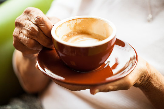 Elderly hands holding a cappuccino