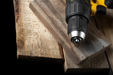 Electric drill closeup on a black background with wood and drills. Electrical tools. Hand battery screwdriver.