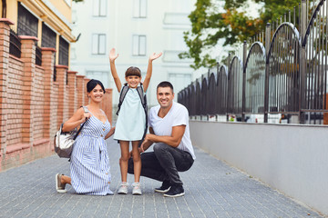 Family and litle girl student with a backpack way to school