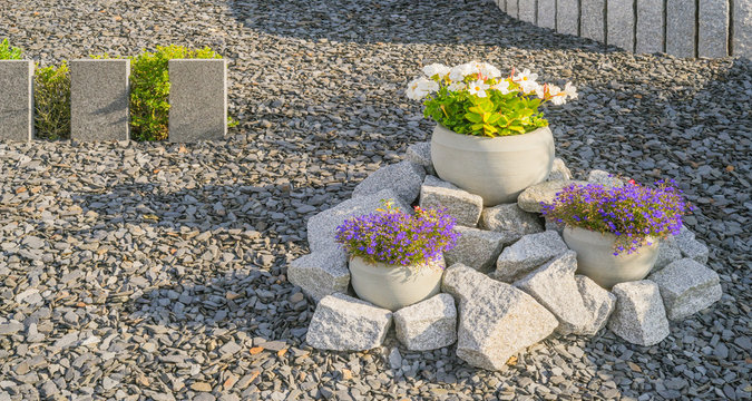 Vorgarten Steingarten mit Stelen aus Granit und Blumen in Blumenkübeln