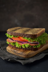 Wholemeal sandwich with vegetables on cutting board