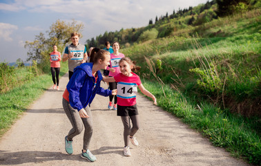 Large group of multi generation people running a race competition in nature.