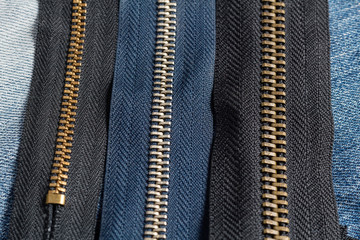 Pack a lot of black navy metal brass zippers stripes with sliders pattern for handmade sewing tailoring leatherwork leathercraft on the blue wooden background