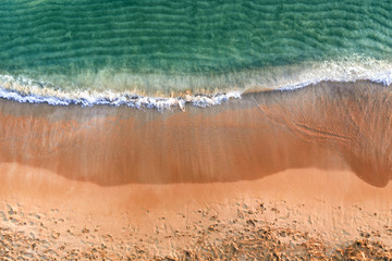 Sandy seashore with turquoise green sea water. Small waves on the beach.
