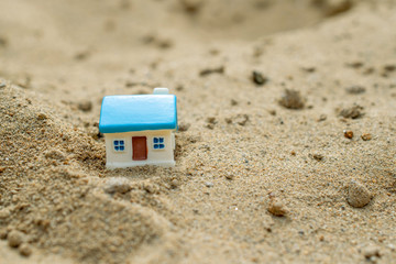 toy house with a blue roof stands on the sand