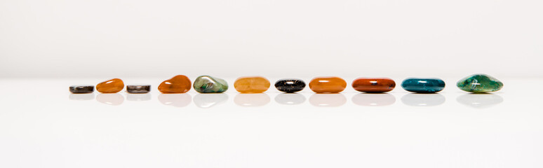 panoramic shot of colorful semiprecious stones on white surface isolated on grey