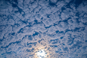 The sun's ray passes through the cirrus clouds in the blue sky.