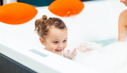 Little girl takes a bath in a hydromassage bathtub.
