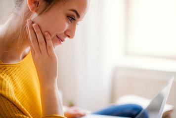 A young female student sitting at the table, using laptop when studying.