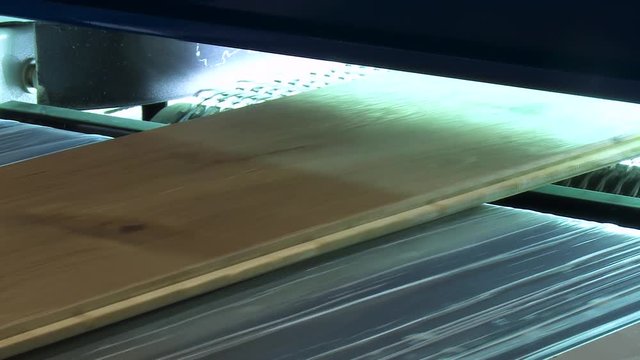 Modern technological factory production with the help of automated conveyor belt of a large batch of laminate and flooring. Furniture factory production line.