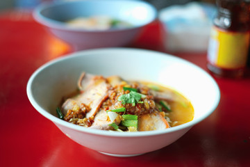 Close up hot noodles and sour soup ( tomyam ) on red dining table