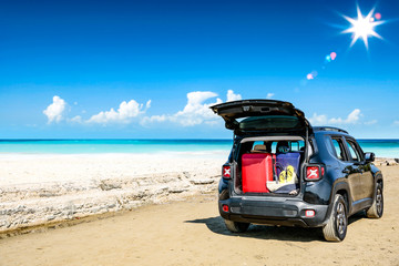 Fototapeta na wymiar Summer car on beach and suitcase 