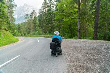 disabled person in an electric wheelchair driving on the street, road