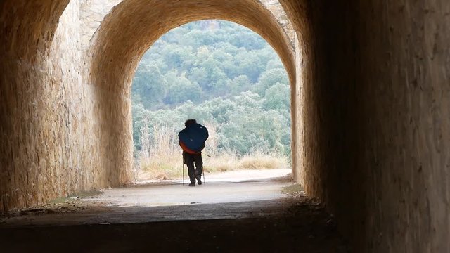 pilgrim with a large backpack goes through the tunnel