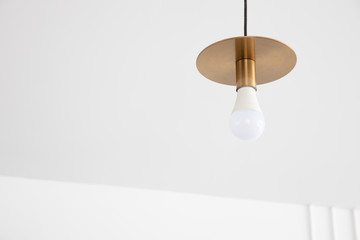 closeup view of retro gold lamp and white bulb hanging from ceiling with copyspace.