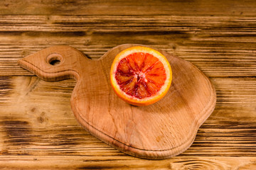 Cutting board with halved sicilian orange on a wooden table