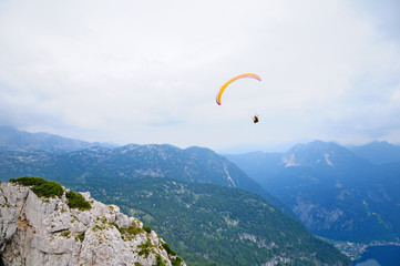 Paraglider flying over mountains in summer day.