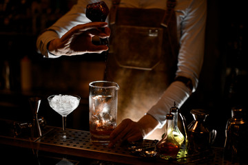 Bartender pouring a cocktail from vial in glass
