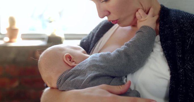 Young mother breastfeeding at home, bonding with baby child toddler