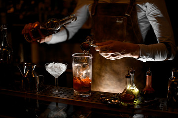 Bartender prepares an alcohol cocktail using jigger