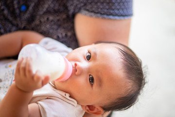 Asian baby girl sucking milk from bottle, Kid drinking milk